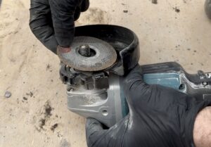 Installing cutting disc on Makita DGA517 angle grinder close up.