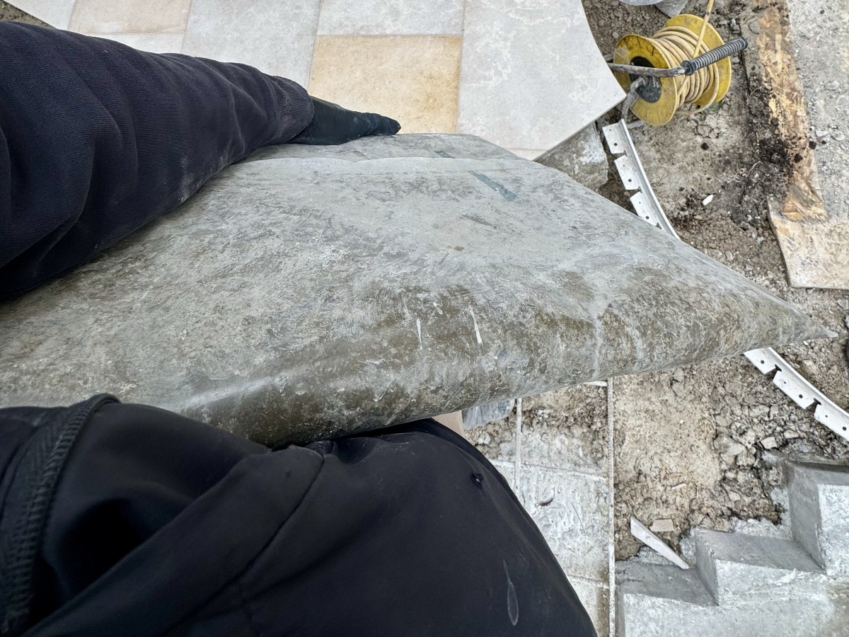 Person holding a flattened slab of leftover concrete that was bagged and left to set the day before on a landscaping project.