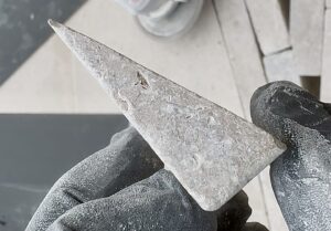 Close-up of a small limestone block paving cut held in hand, showing precise angled cutting for detailed paving pattern installation