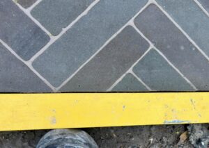Spirit level placed against block paving edge showing uneven gap and imperfect straight cut.